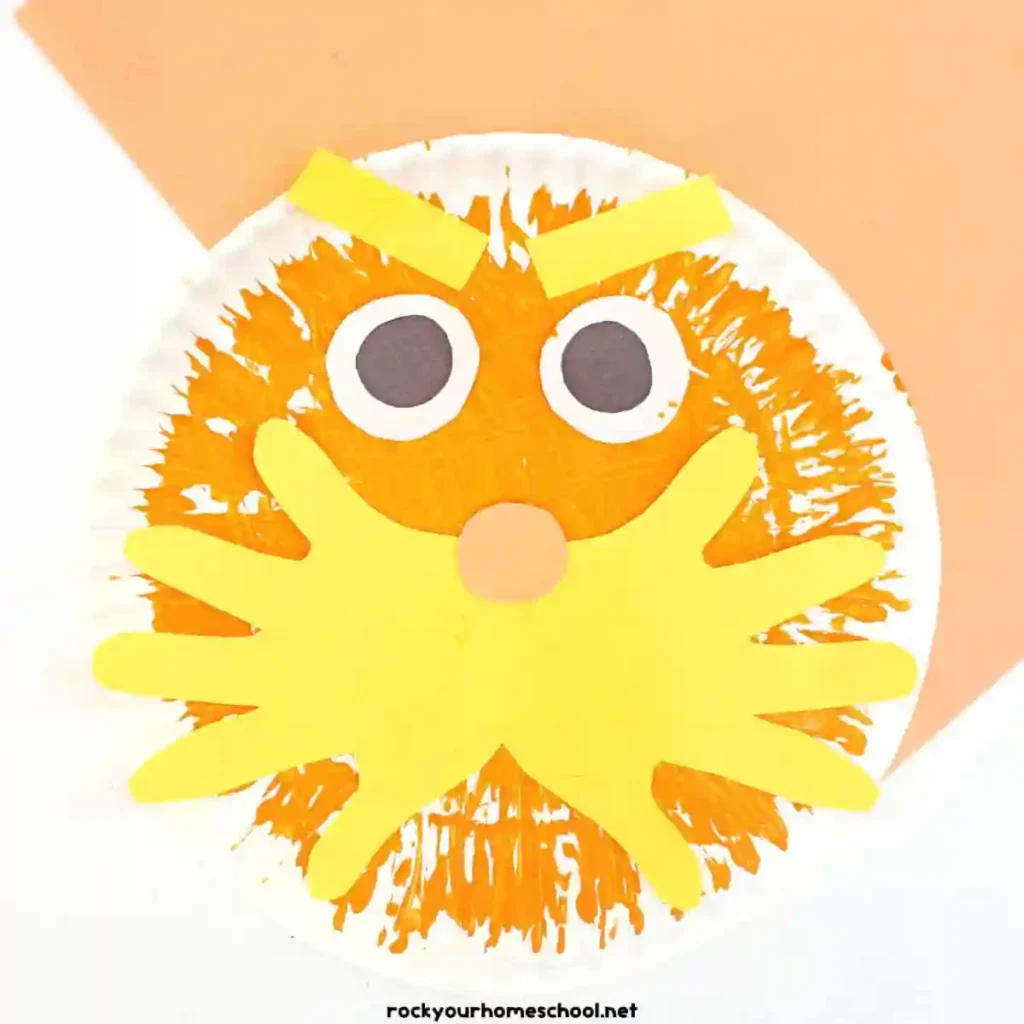 Dr Seuss Crafts for Kids - Cultivating Brilliant Minds a paper plate painted orange with a construction paper face to look like the lorax