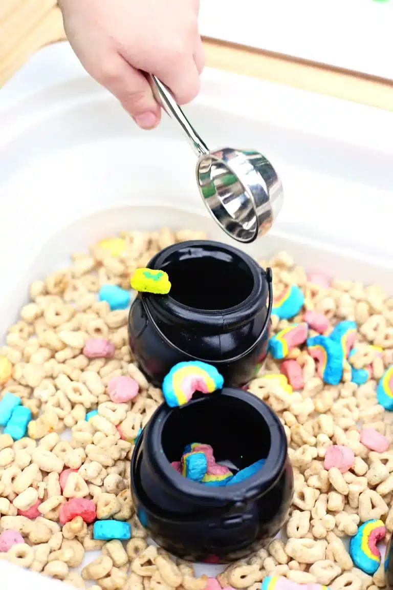 a kid holding a measuring cup that has a lucky charm marshmallow in it