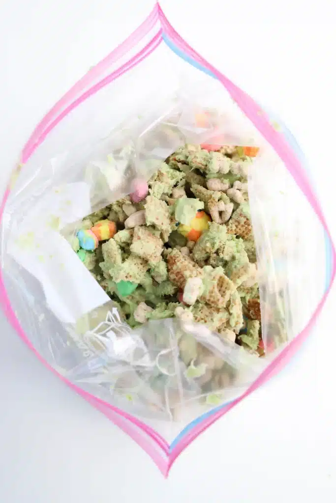 Lucky Charms Puppy Chow for St. Patrick's Day - Cultivating Brilliant Minds chex mix and lucky charms coated with green melted candy melts in a plastic bag