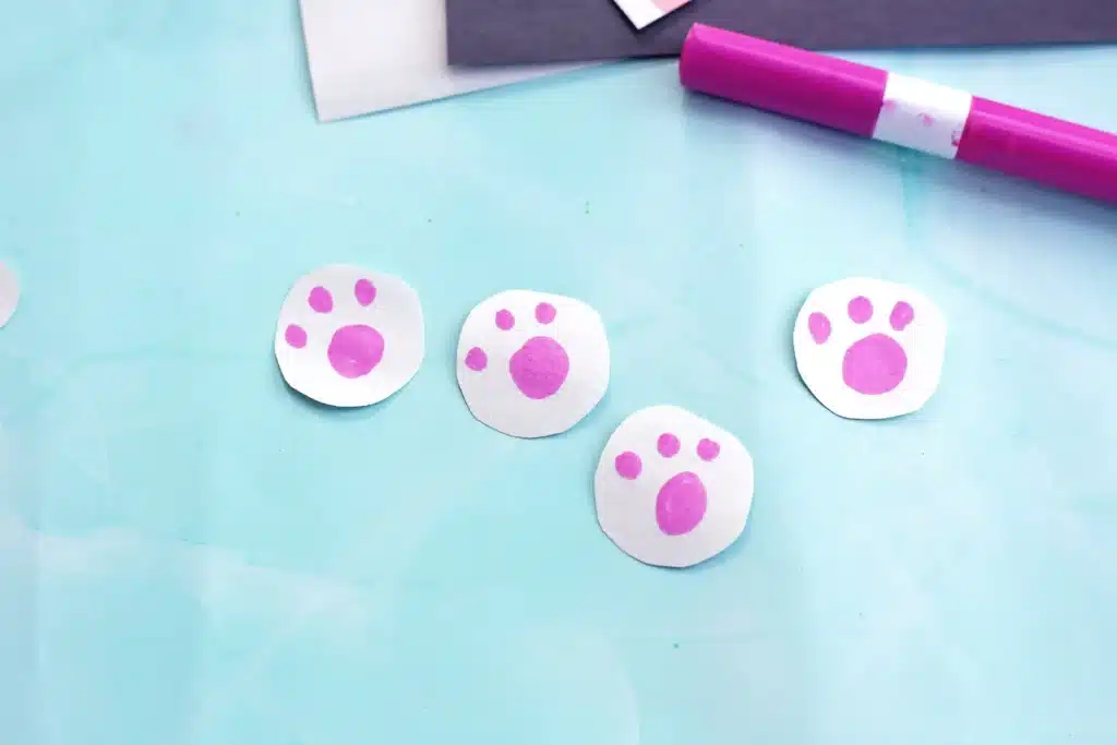 Little Debbie Easter Bunny Cakes - Cultivating Brilliant Minds circles cut out of white construction paper with pink paw prints drawn on
