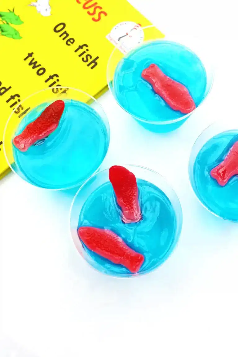 blue jello cups with red swedish fish on top next to Dr. Seuss's One fish, two fish, red fish, blue fish book