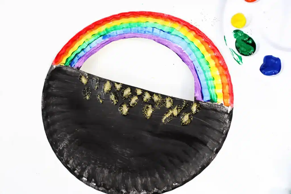 Paper Plate Pot of Gold with Fingerprint Coins - Cultivating Brilliant Minds a paper plate with a semi circle cut out of the top painted to look like a pot of gold with a rainbow on top