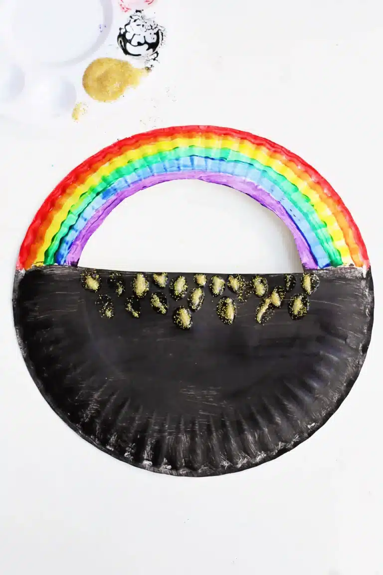 a paper plate with a semi circle cut out of the top painted to look like a pot of gold with a rainbow on top