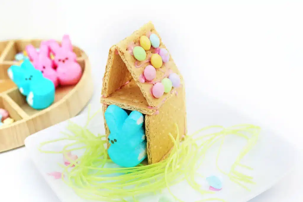 Peeps House STEM Challenge - Cultivating Brilliant Minds a Peeps House STEM Challenge that uses graham crackers, icing, and m&ms to build a house for a peeps bunny on top of edible easter grass