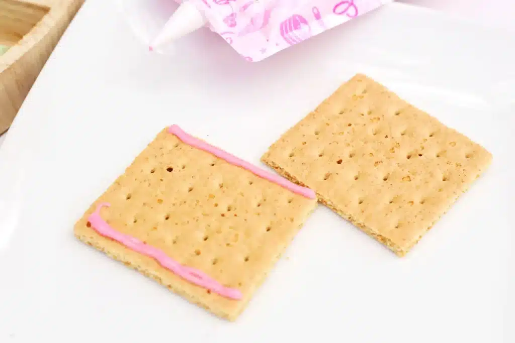 Peeps House STEM Challenge - Cultivating Brilliant Minds two graham crackers, one with pink icing on the edges