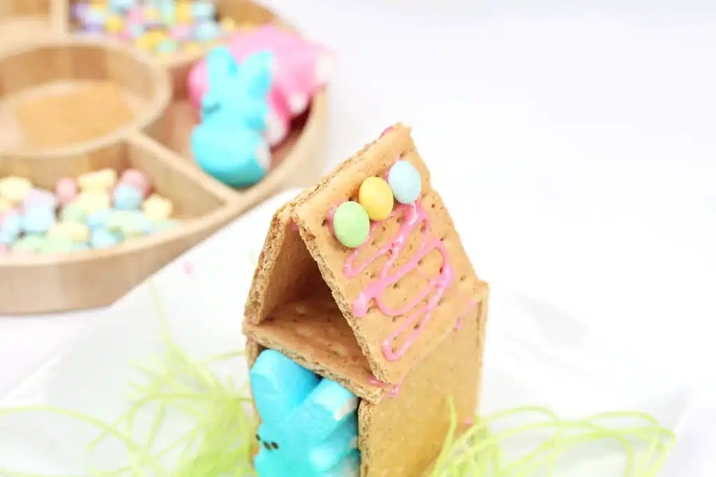 Peeps House STEM Challenge - Cultivating Brilliant Minds a house made out of four graham crackers stuck together with icing with pastel m&ms on the roof