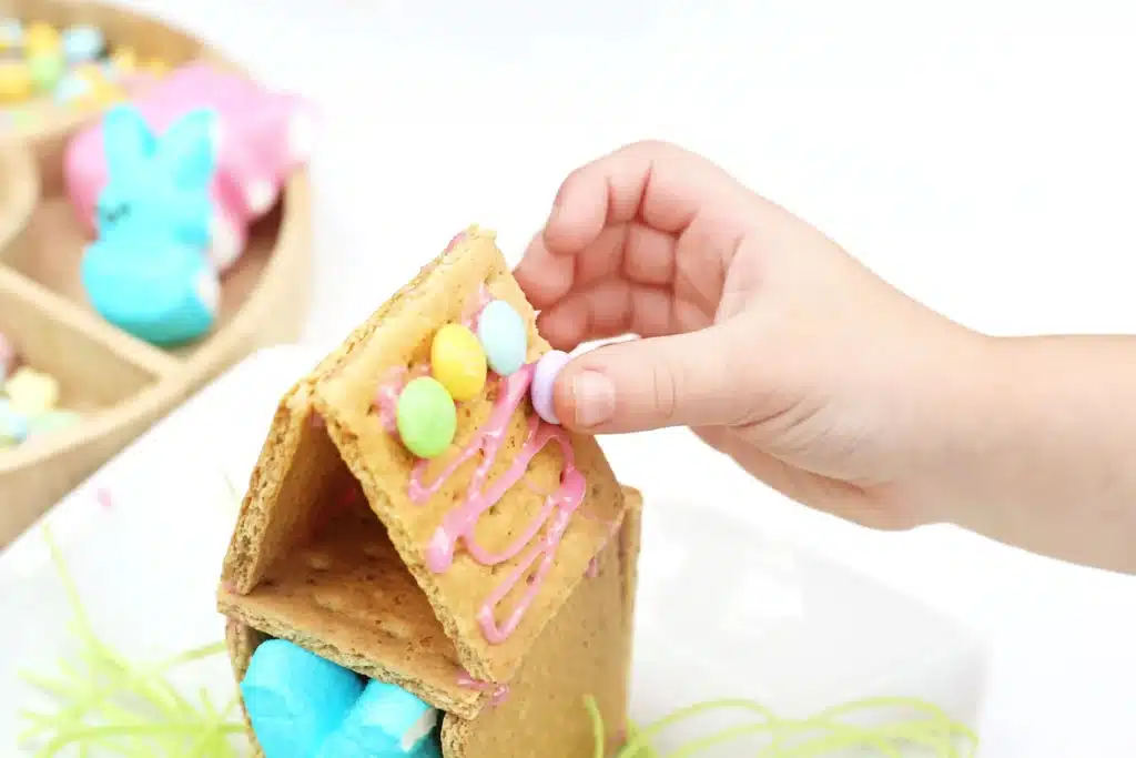 Peeps House STEM Challenge - Cultivating Brilliant Minds a house made out of four graham crackers stuck together with icing with pastel m&ms on the roof