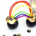 Pot of Gold Playdough Tray - Cultivating Brilliant Minds two black caludron pots with yellow playdough in each and rainbow color pipe cleaners sticking in each to create a rainbow