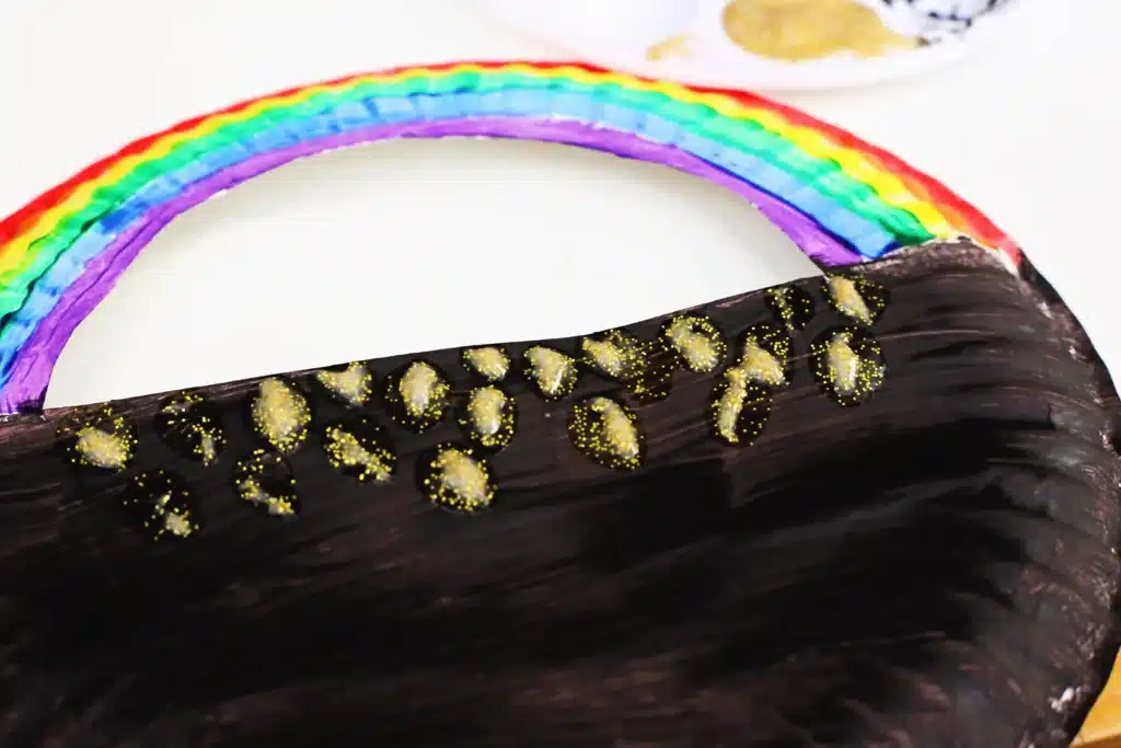 Paper Plate Pot of Gold with Fingerprint Coins - Cultivating Brilliant Minds a paper plate with a semi circle cut out of the top painted to look like a pot of gold with a rainbow on top