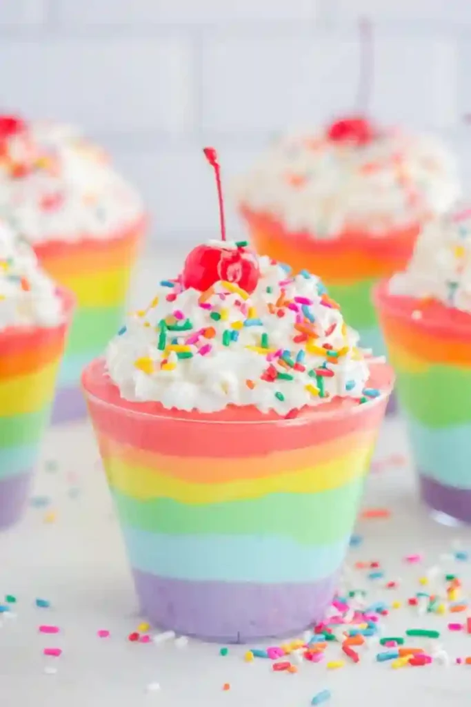 St. Patrick's Day Treats for Kids - Cultivating Brilliant Minds a pudding cup with layers of colored pudding in rainbow order. It has whipped cream, sprinkles, and a cherry on top