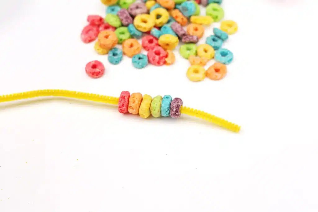 Froot Loops Rainbow Snack - Cultivating Brilliant Minds a pipe cleaner with froot loops threaded on a pipe cleaner in rainbow order