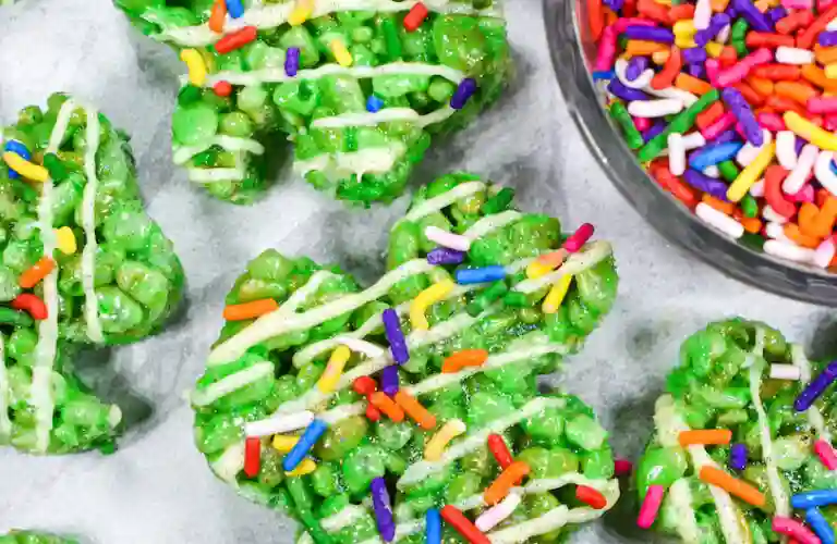 St. Patrick's Day Treats for Kids - Cultivating Brilliant Minds green rice krispie treats that are in the shape of a shamrock and have colorful sprinkles on top