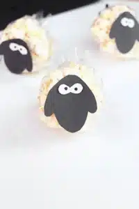 Sheep Popcorn Balls - Cultivating Brilliant Minds a popcorn ball with a construction paper sheep face on it to make a sheep popcorn ball