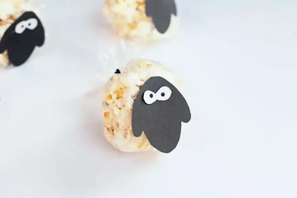 Sheep Popcorn Balls - Cultivating Brilliant Minds a popcorn ball with a construction paper sheep face on it to make a sheep popcorn ball