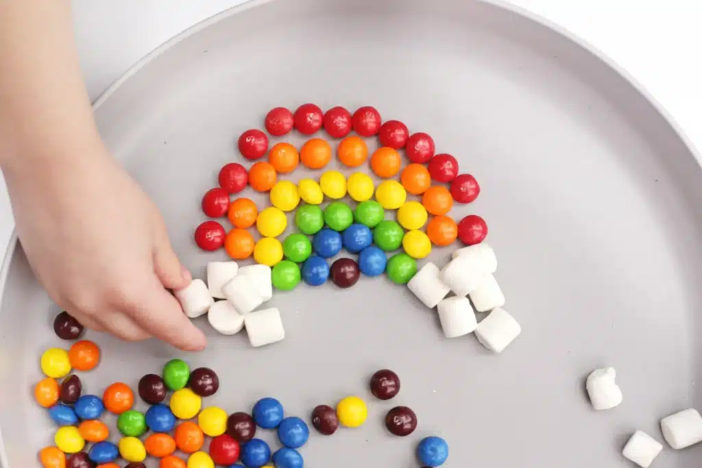 Skittles Rainbow Fine Motor Activity - Cultivating Brilliant Minds skittles and marshmallows organized into a rainbow on a plate