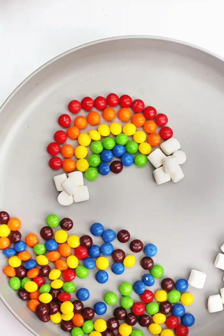 skittles and marshmallows organized into a rainbow on a plate