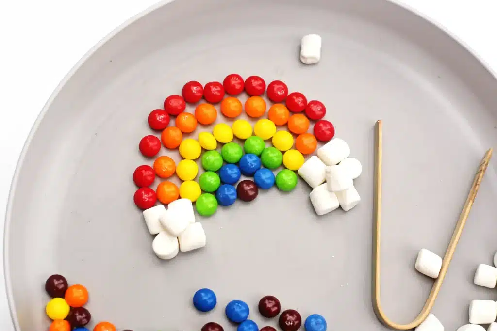 Skittles Rainbow Fine Motor Activity - Cultivating Brilliant Minds skittles and marshmallows organized into a rainbow on a plate