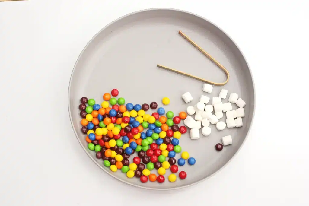 Skittles Rainbow Fine Motor Activity - Cultivating Brilliant Minds skittles, marshmallows, and tongs on a plate