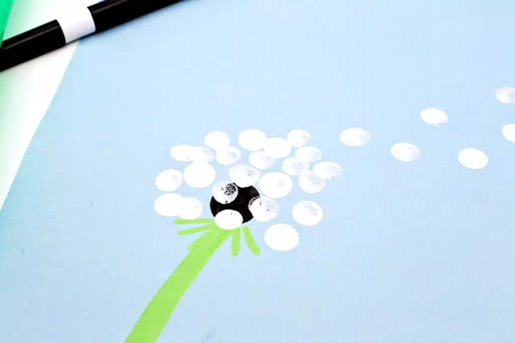 Fingerprint Dandelions - Cultivating Brilliant Minds a dandelion painted on a blue piece of paper with fingerprints for the flower