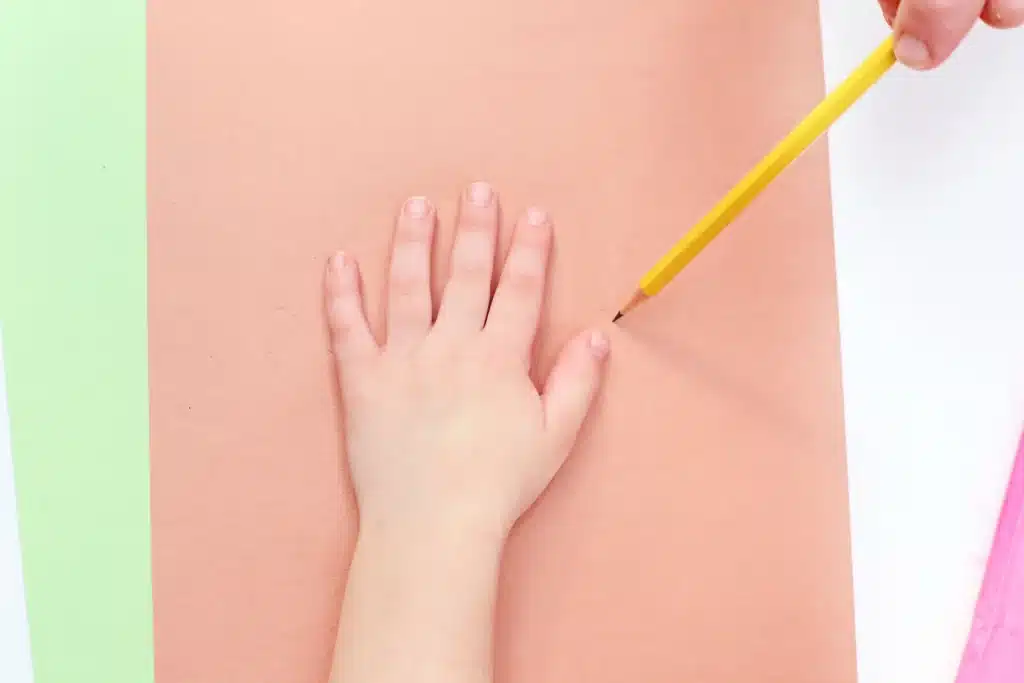 Handprint Cherry Blossom Tree - Cultivating Brilliant Minds a kid tracing his hand on brown construction paper