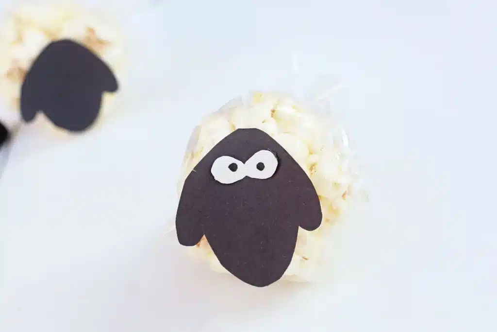 Sheep Popcorn Balls - Cultivating Brilliant Minds a popcorn ball with a construction paper sheep face on it to make a sheep popcorn ball