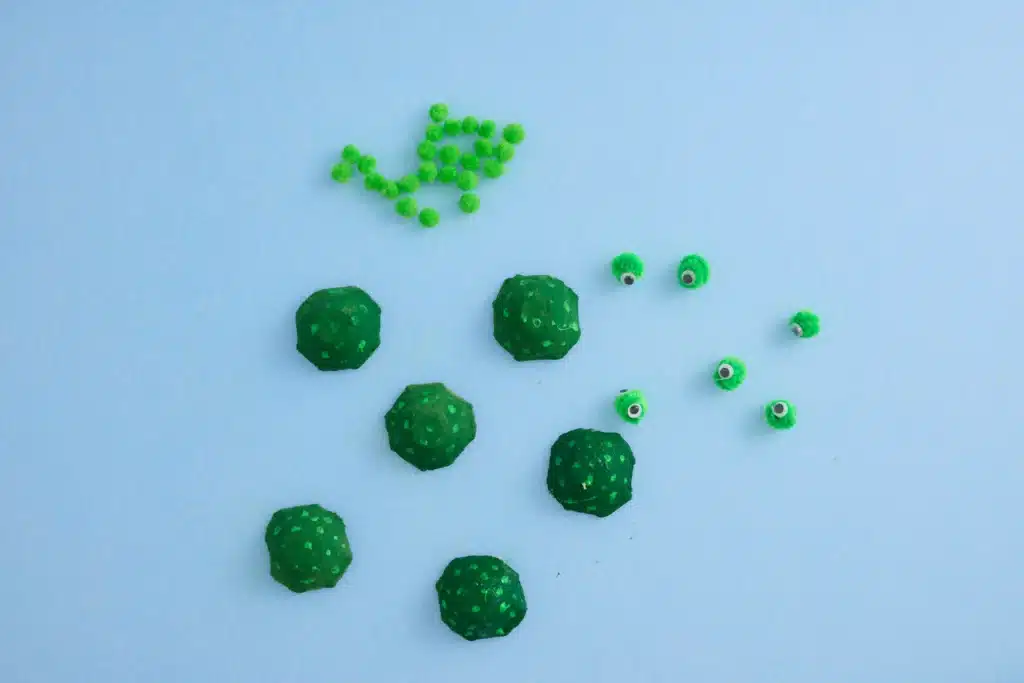 Egg Carton Turtle Craft - Cultivating Brilliant Minds pipe cleaners rolled into a ball with googly eyes glued on next to egg carton cups painted green