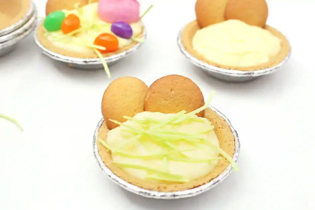 Peeps banana pudding mini pies - Cultivating Brilliant Minds a mini banana pudding pie with edible easter grass on top and nilla wafers