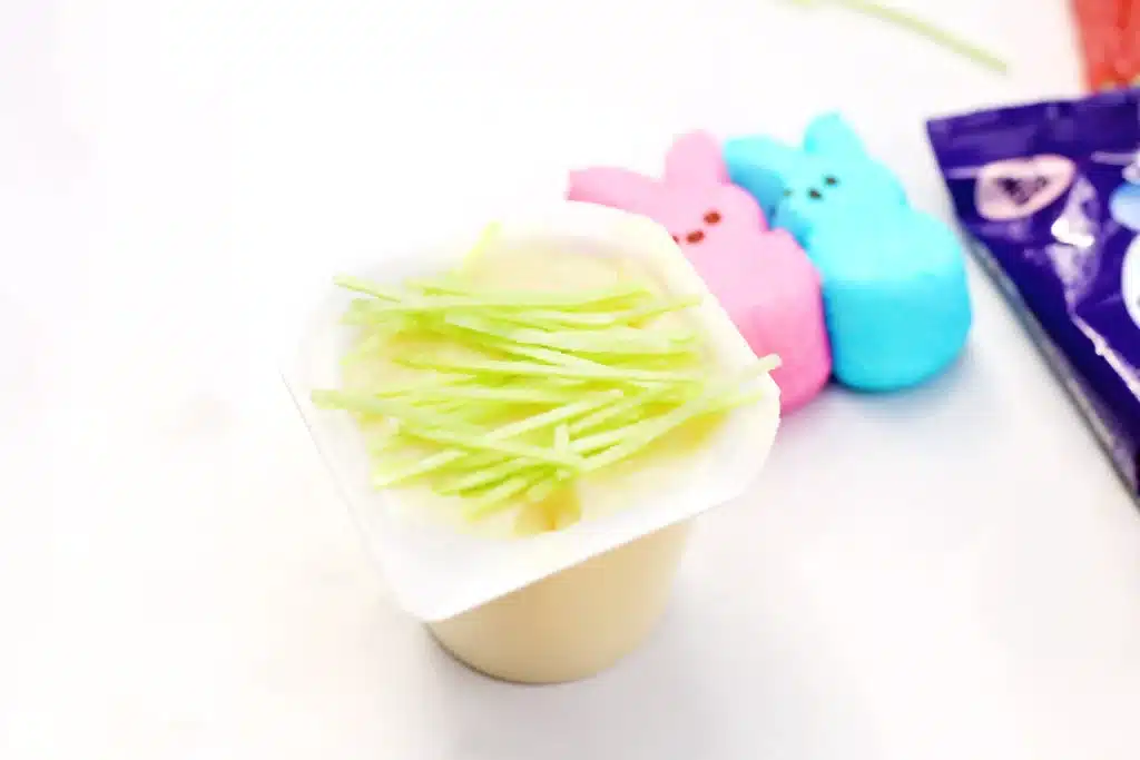 Easter Basket Pudding Cups - Cultivating Brilliant Minds a vanilla pudding cup with edible Easter grass on top