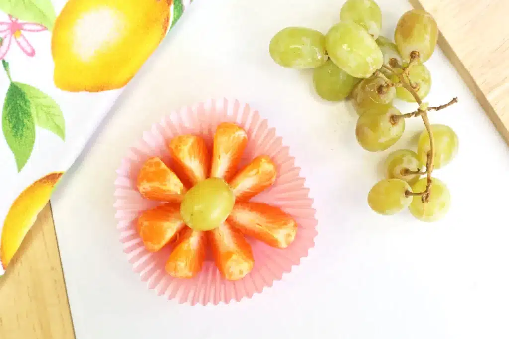Flower Garden Lunch - Cultivating Brilliant Minds orange slices and a green grape arranged to look like a flower