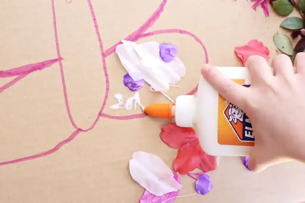 Butterfly Nature Collage - Cultivating Brilliant Minds a kid gluing flowers onto the cardboard butterfly