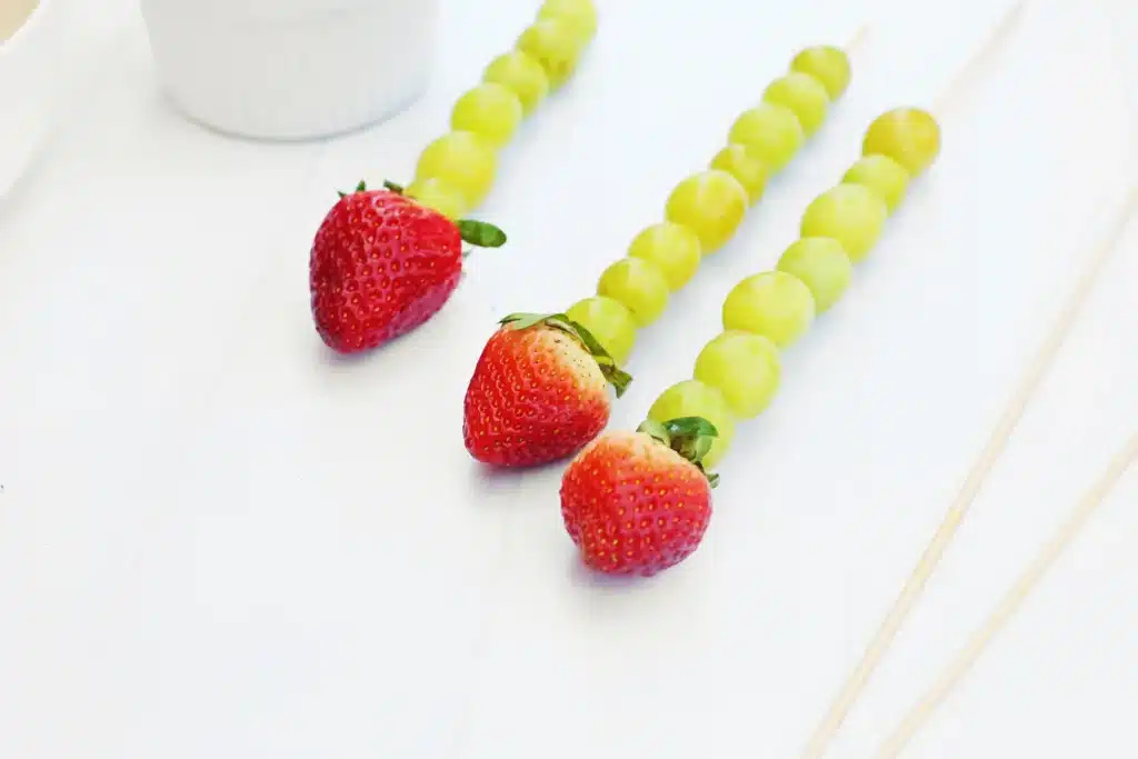 Caterpillar Grape Skewers - Cultivating Brilliant Minds skewers with green grapes on it and a strawberry on top
