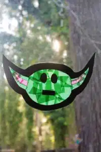a baby yoda sun catcher hanging on a window