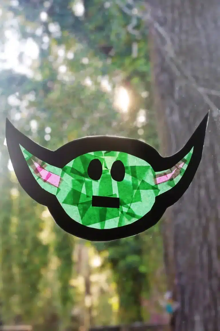 a baby yoda sun catcher hanging on a window