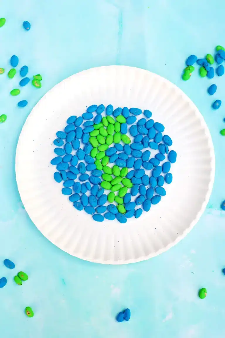an earth craft for kids that uses green and blue dyed pinto beans glued to a paper plate in the shape of the earth