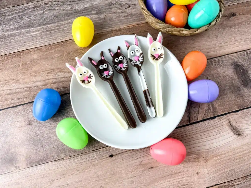 Bunny Chocolate Spoons - Cultivating Brilliant Minds chocolate spoons decorated to look like bunnies on a white plate next to plastic easter eggs