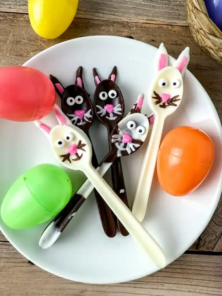 Bunny Chocolate Spoons - Cultivating Brilliant Minds chocolate spoons decorated to look like bunnies on a white plate next to plastic easter eggs