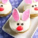 Bunny Cupcakes for Easter - Cultivating Brilliant Minds vanilla cupcakes decorated to look like a bunny with chocolate chip eyes, a jelly bean nose, and cut marshmallows dipped in sanding sugar for ears.