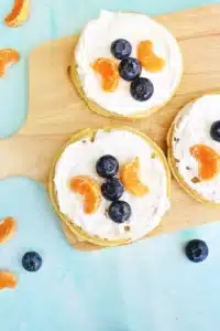 waffles with whipped cream and blueberries and oranges arranged to look like a butterfly