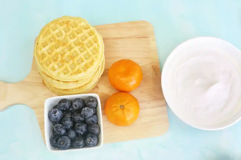 Butterfly Garden Waffles: A Spring Breakfast Idea For Kids - Cultivating Brilliant Minds ingredients for the spring breakfast for kids: waffles, whipped cream, blueberries, and oranges