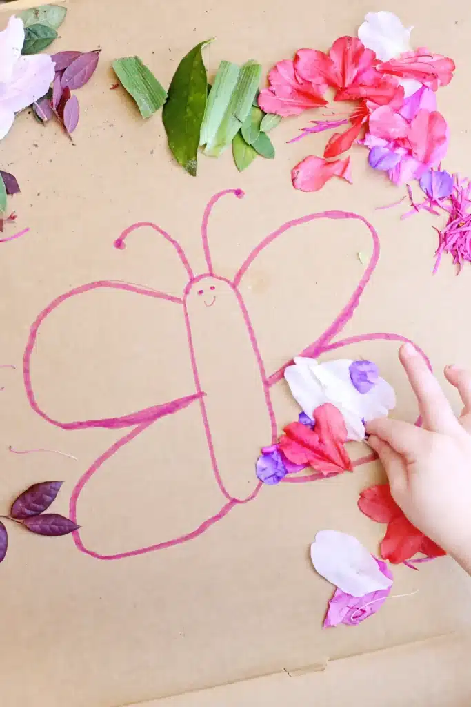 Butterfly Nature Collage - Cultivating Brilliant Minds a kid gluing flowers onto the cardboard butterfly