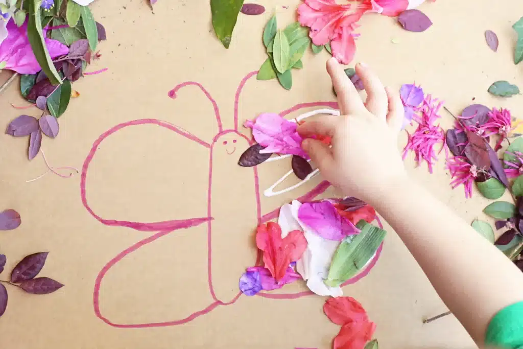 Butterfly Nature Collage - Cultivating Brilliant Minds a kid gluing flowers onto the cardboard butterfly