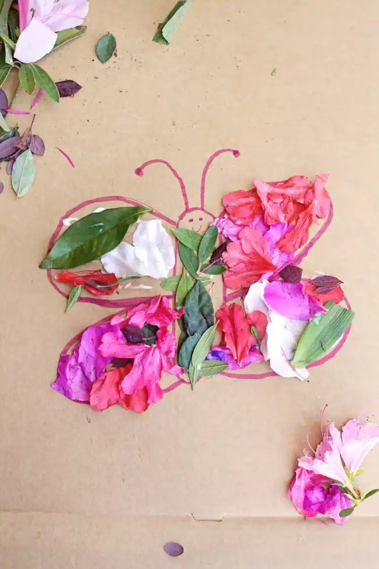 a butterfly drawn on cardboard with flowers and leaves glued on it