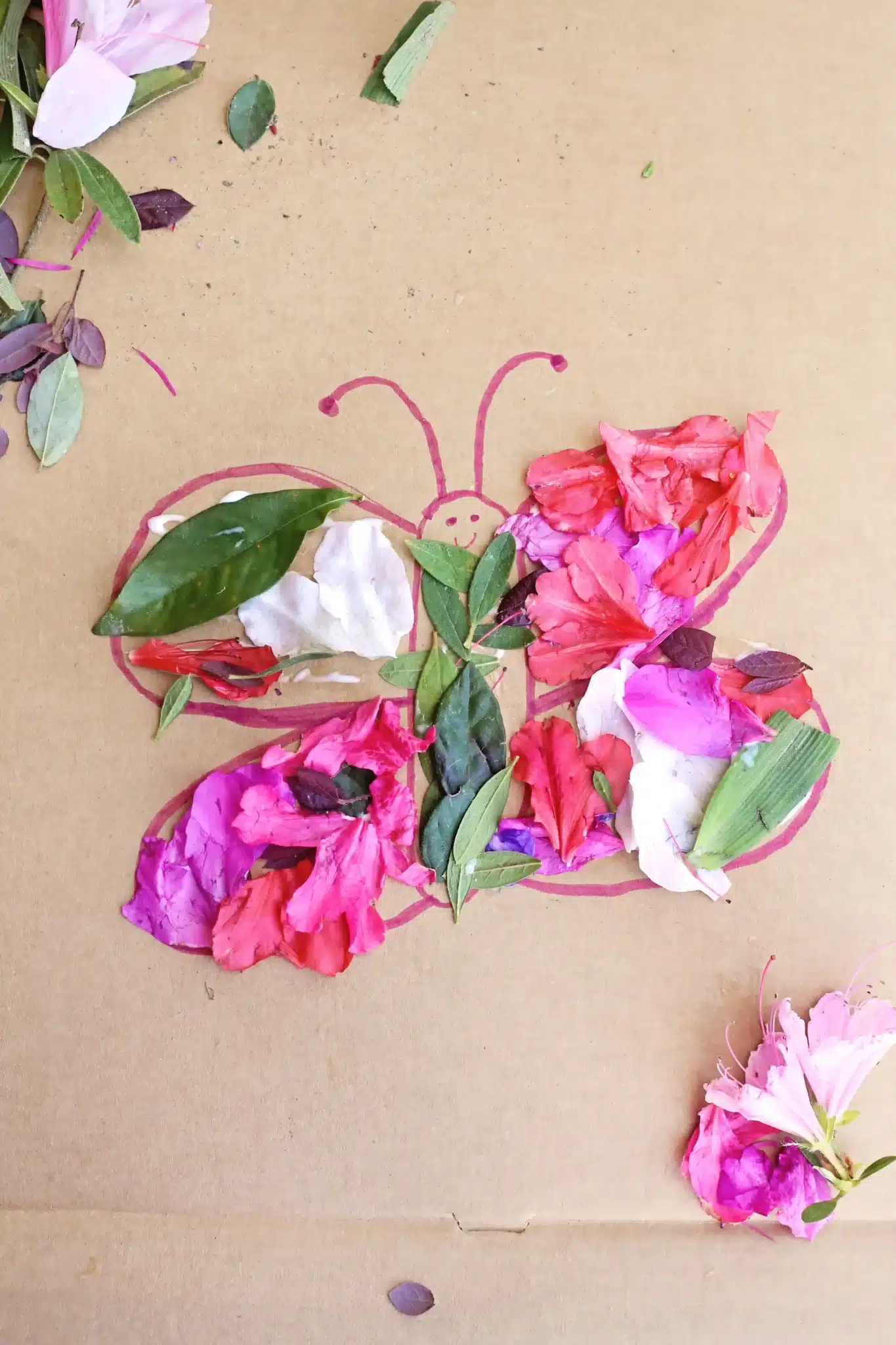 a butterfly drawn on cardboard with flowers and leaves glued on it