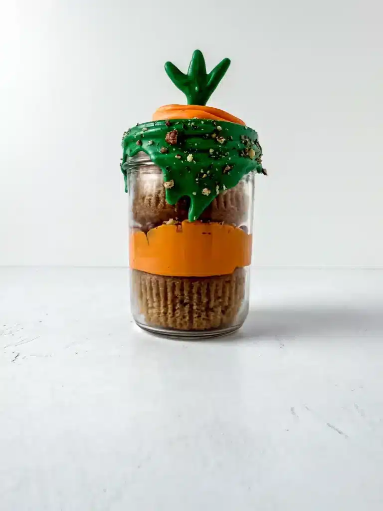 Carrot Cake Jars For Easter - Cultivating Brilliant Minds a jar with two cupcakes in it with orange and green icing to look like a carrot