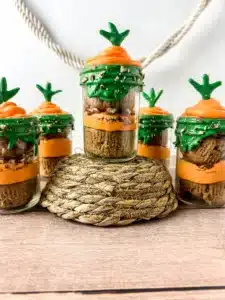 a jar with two cupcakes in it with orange and green icing to look like a carrot