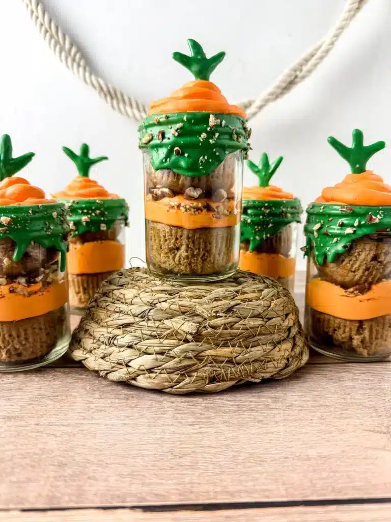 a jar with two cupcakes in it with orange and green icing to look like a carrot