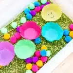 Spring Caterpillar Color Sorting Sensory Bin - Cultivating Brilliant Minds a spring color sorting sensory bin with green split peas, colored cupcale liners, and pom poms