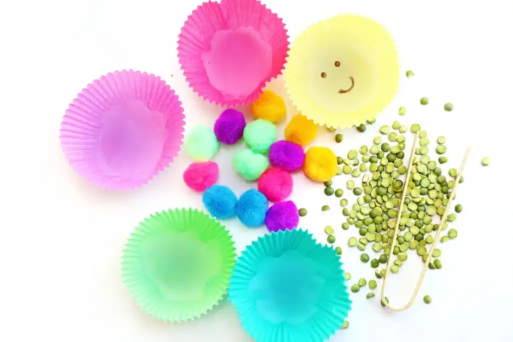 Spring Caterpillar Color Sorting Sensory Bin - Cultivating Brilliant Minds colored cupcake liners, pom poms, and peas
