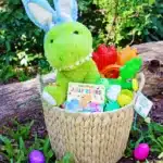 Dinosaur Easter Basket For Kids - Cultivating Brilliant Minds a dinosaur easter basket for kids that has a plush dinosaur, a dinosaur book, plastic easter eggs decorated to look like dinos, and dinosaur toys.