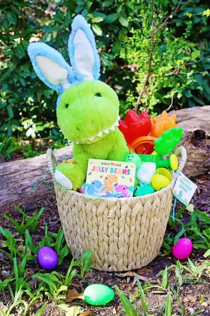Dinosaur Easter Basket For Kids - Cultivating Brilliant Minds a dinosaur easter basket for kids that has a plush dinosaur, a dinosaur book, plastic easter eggs decorated to look like dinos, and dinosaur toys.